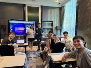 ผู้เรียนนั่งเรียนในห้องอบรมที่มีจอแสดงสไลด์ ชูนิ้วโป้ง